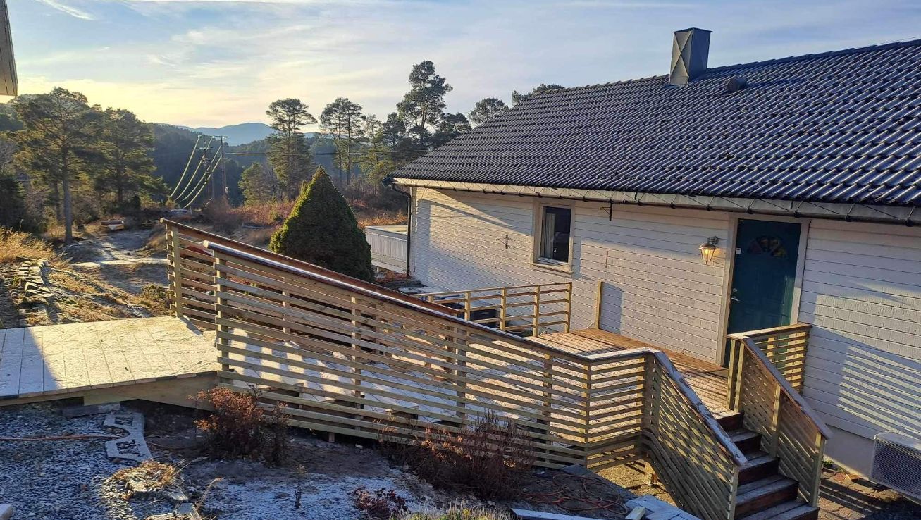 Enebolig med nybygd rampe og trapper i tre foran inngangsdør.