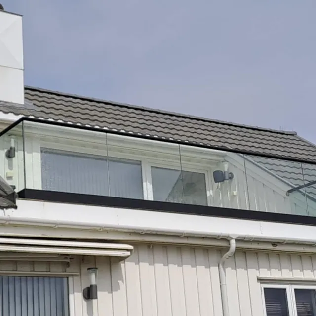 Enebolig med takterrasse og rekkverk i glass montert på loftsetasje.