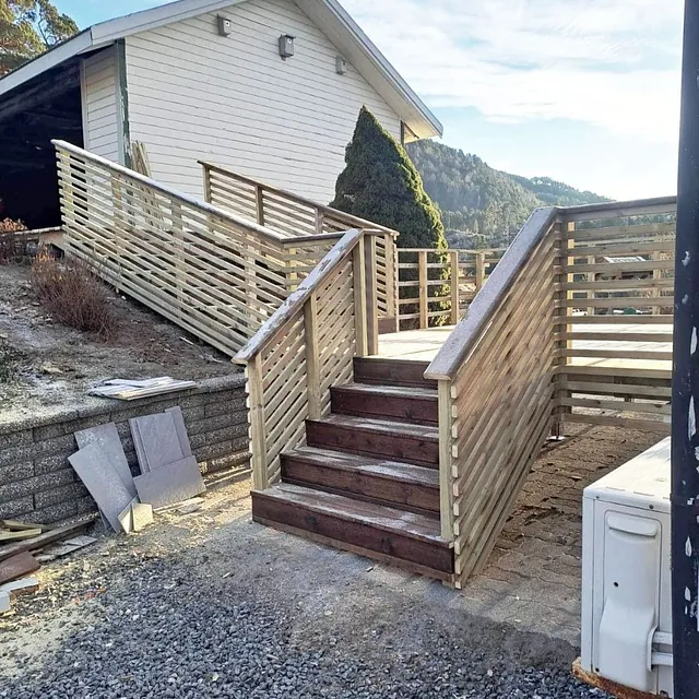 Nybygd tretrapp med rekkverk i treverk som leder opp til husinngang.