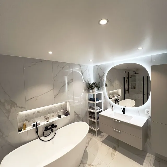 Lyst bad med frittstående badekar, servant og speil med lys.