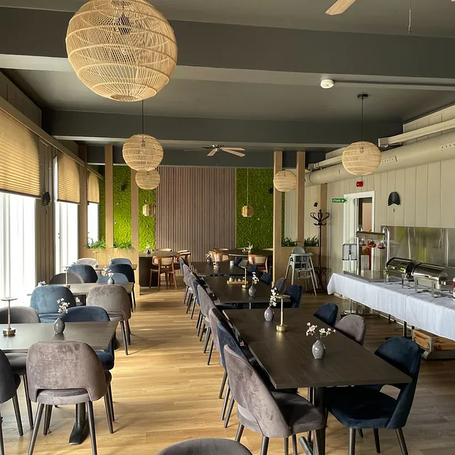 Ferdig innredet restaurant med mørke bord, polstrede stoler og buffet langs veggen.