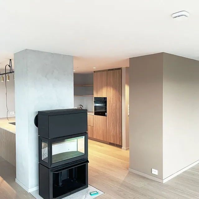 Moderne stue med peis, åpen kjøkkenløsning og lyse tregulv.