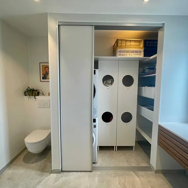 Vaskerom med oppbevaring, vaskemaskin og praktisk løsning bak skyvedører.