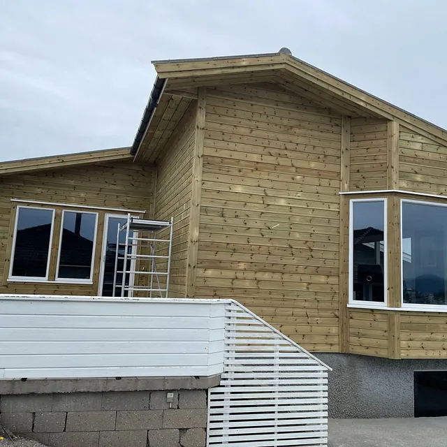 Hus med ny kledning i trepanel og store vinduer ut mot terrasse.