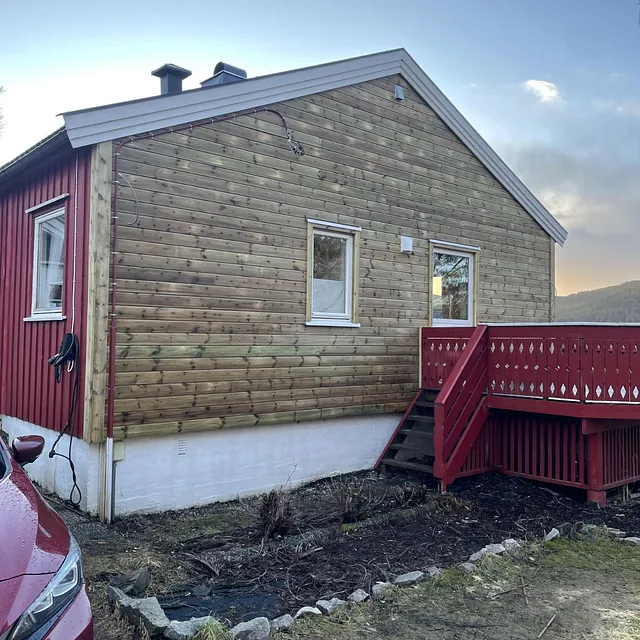 Enebolig med ny trepanel på gavlvegg, rødmalt terrasse og trapp.