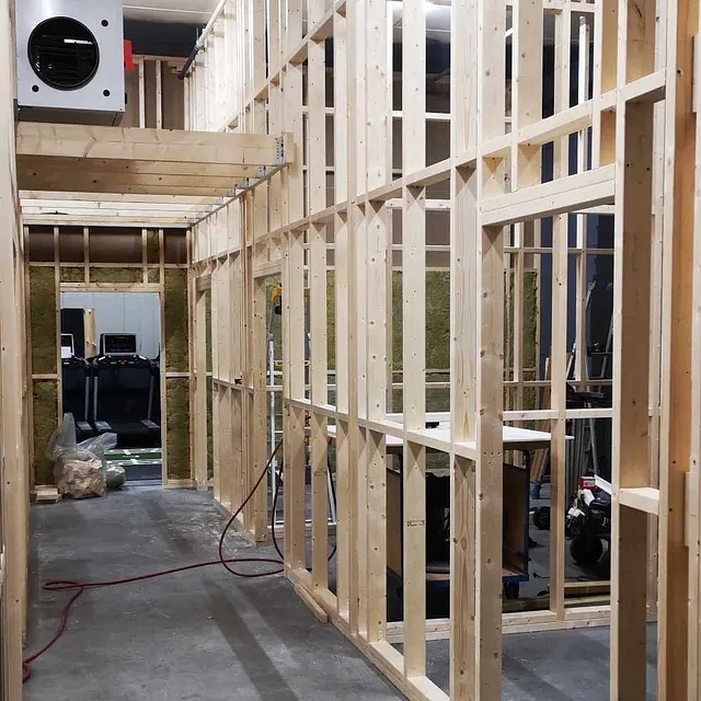 Smal gang under oppføring med trestenderverk og åpen takløsning.