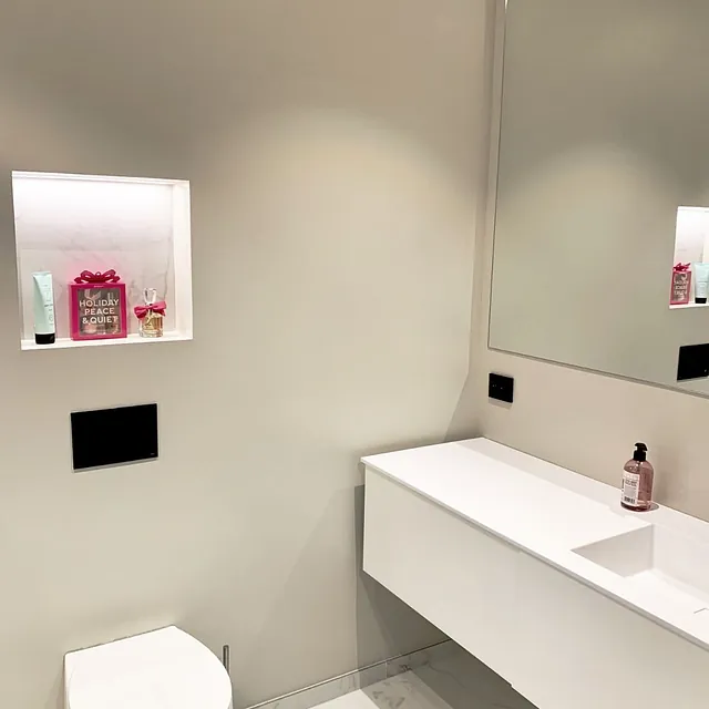 Moderne gjestebad med vegghengt toalett, hvit servant og stor speilflate.