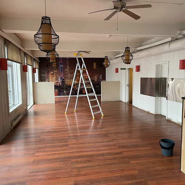 Tomt lokale med trelaminatgulv, stige i midten og store vinduer langs veggen.