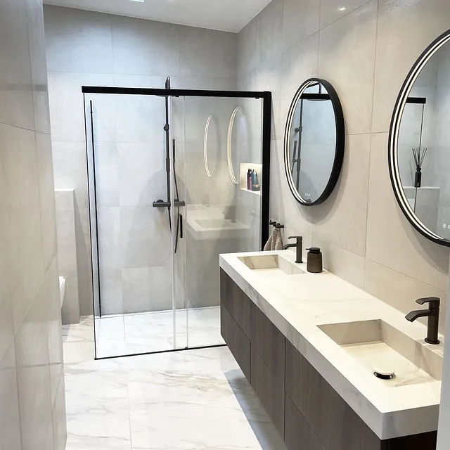 Bad med doble servanter, runde speil og dusj med glassdør.