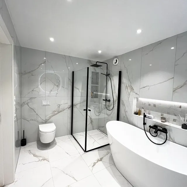 Lyst bad med frittstående badekar, dusj og vegghengt toalett.