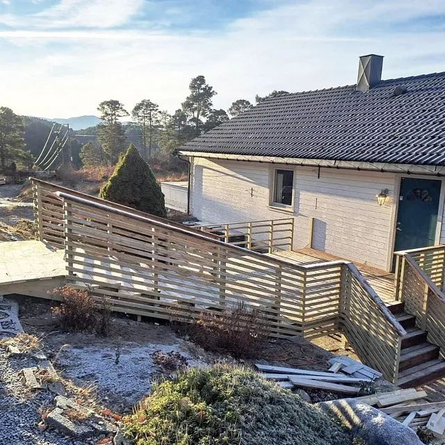 Enebolig med nybygd rampe og trapp i tre som fører til hovedinngang.