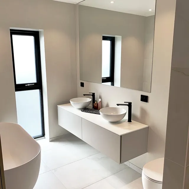 Lyst bad med frittstående badekar, dobbel servant og stort speil.