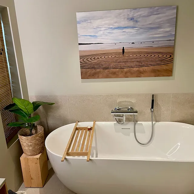 Bad med frittstående badekar, plante og stort bilde på veggen.