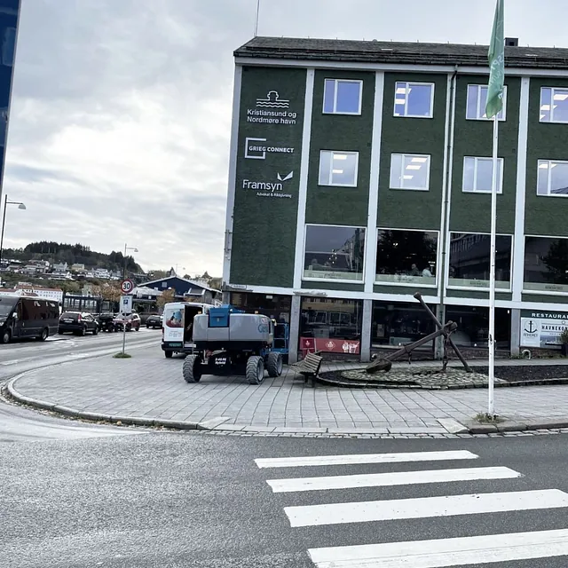 Grønn bygård med nymonterte firmalogoer på fasaden ved gatehjørne.